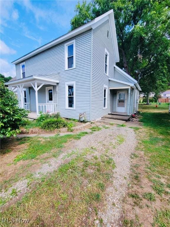 rear view of house featuring a lawn and covered porch