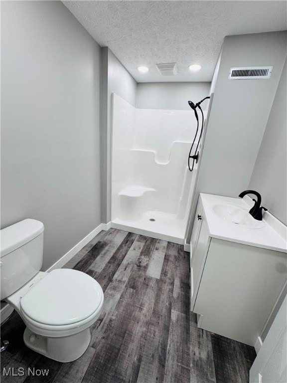 bathroom with a shower, hardwood / wood-style floors, a textured ceiling, toilet, and vanity