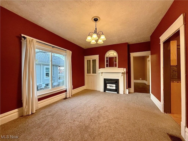 unfurnished living room with carpet floors, a textured ceiling, and an inviting chandelier