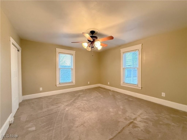 carpeted spare room featuring a healthy amount of sunlight and ceiling fan