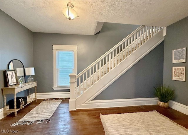 staircase featuring hardwood / wood-style floors and a textured ceiling