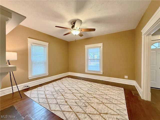 unfurnished room featuring dark wood-type flooring, ceiling fan, and a textured ceiling