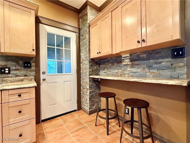 interior space with tasteful backsplash, light brown cabinetry, and light stone countertops