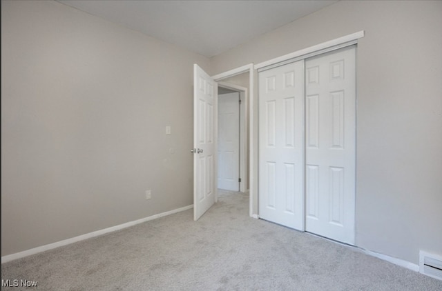 unfurnished bedroom with light carpet and a closet