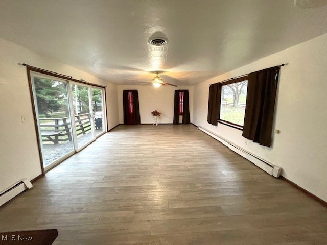 spare room with wood-type flooring, baseboard heating, and ceiling fan