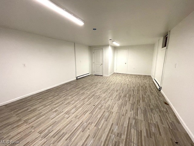 basement with a baseboard heating unit and hardwood / wood-style flooring