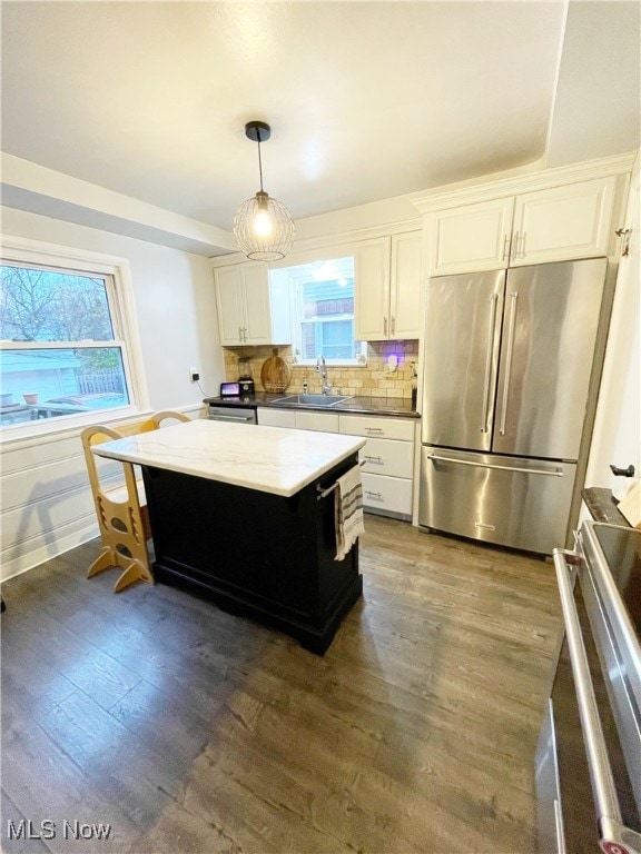 kitchen featuring stainless steel appliances, dark hardwood / wood-style flooring, decorative light fixtures, decorative backsplash, and white cabinets