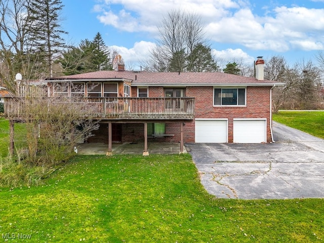 rear view of house with a garage, a deck, and a lawn