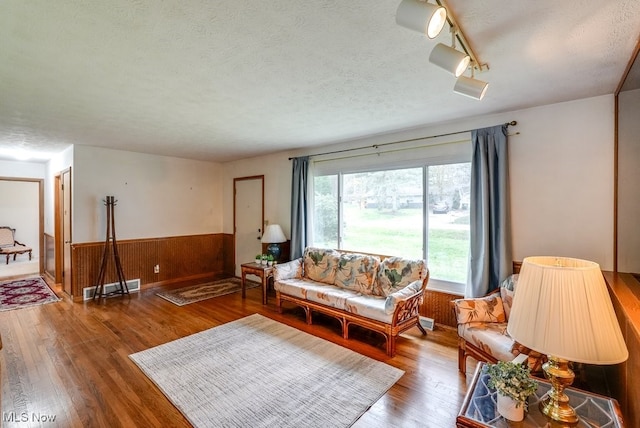 living room featuring hardwood / wood-style flooring, wood walls, and a textured ceiling