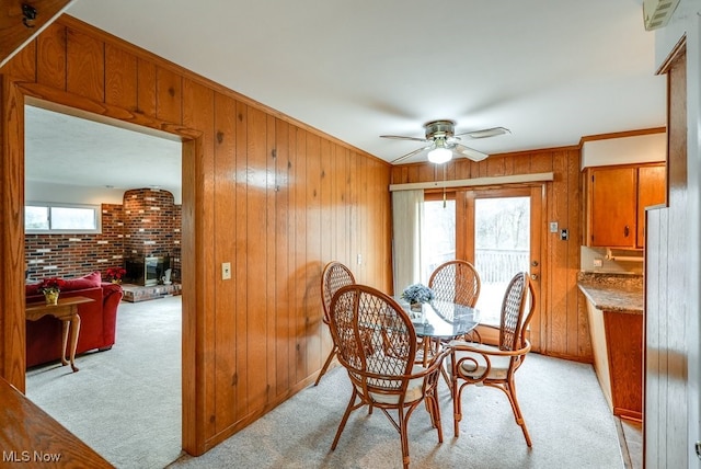 dining space featuring light carpet, wooden walls, and a healthy amount of sunlight