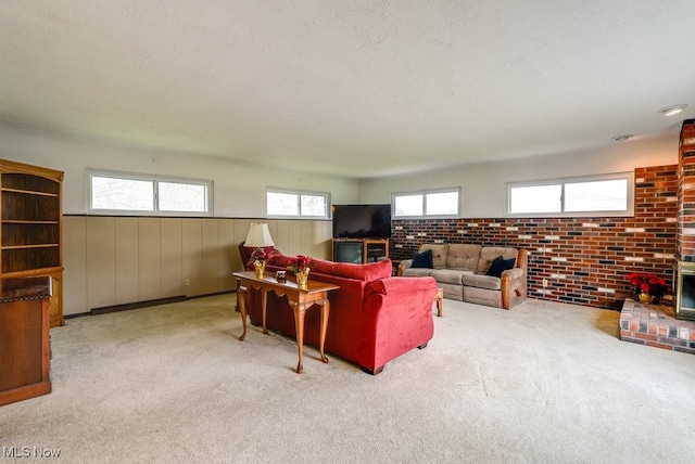 carpeted living room with wood walls, a textured ceiling, brick wall, and a brick fireplace