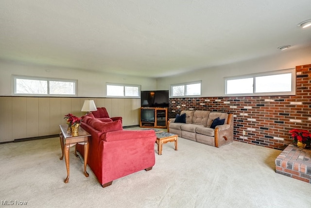 carpeted living room with wooden walls, a textured ceiling, and brick wall