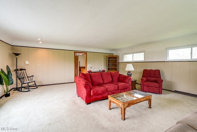 living room featuring wood walls, light colored carpet, and a textured ceiling