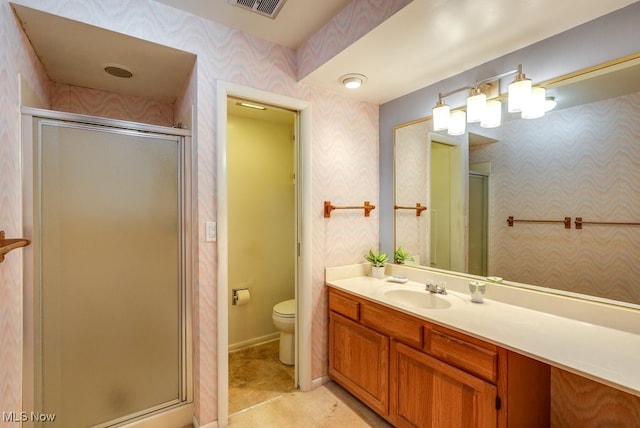 bathroom featuring a shower with door, vanity, and toilet