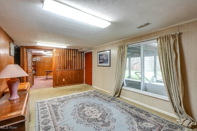 interior space with carpet, a textured ceiling, crown molding, and wood walls