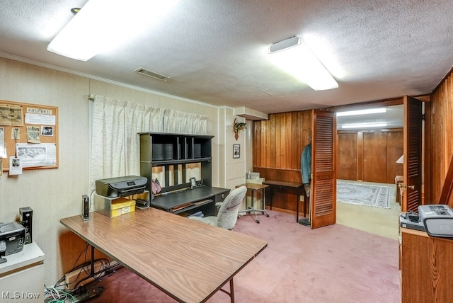 carpeted office with wooden walls, a textured ceiling, and ornamental molding