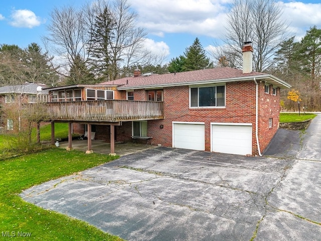 view of front of property with a garage, a deck, and a front lawn