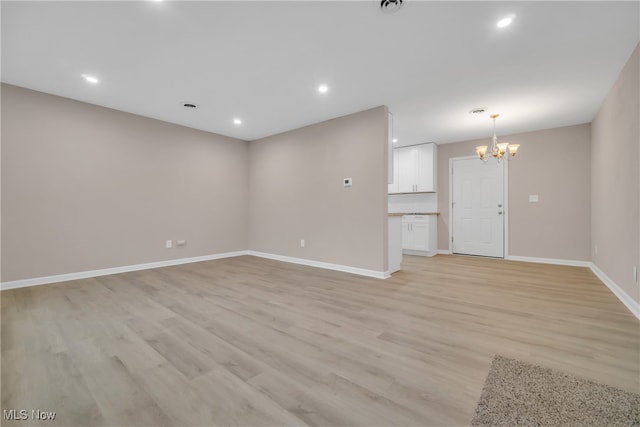 unfurnished living room with a chandelier and light wood-type flooring