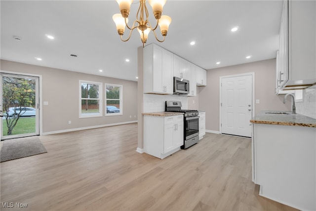 kitchen featuring white cabinets, sink, hanging light fixtures, stainless steel appliances, and a chandelier