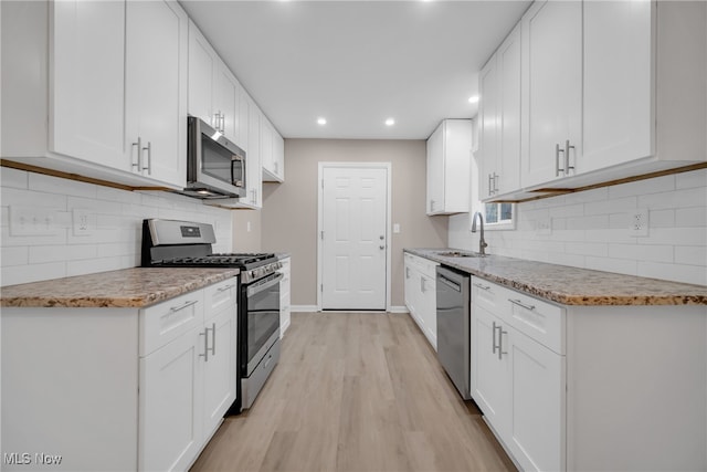 kitchen featuring white cabinets, sink, stainless steel appliances, and light hardwood / wood-style flooring