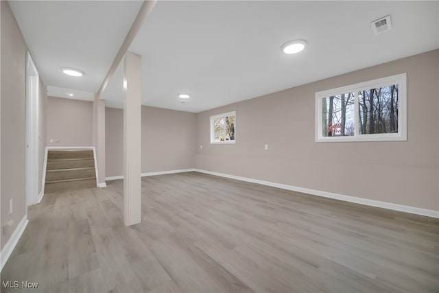 basement with plenty of natural light and light hardwood / wood-style flooring