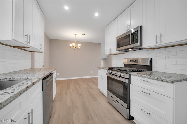 kitchen featuring backsplash, stainless steel appliances, an inviting chandelier, light hardwood / wood-style flooring, and white cabinetry