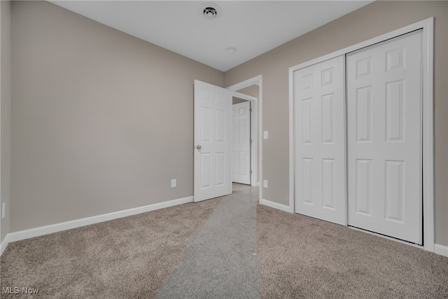 unfurnished bedroom featuring light colored carpet and a closet