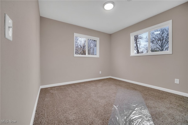 unfurnished room featuring plenty of natural light and carpet