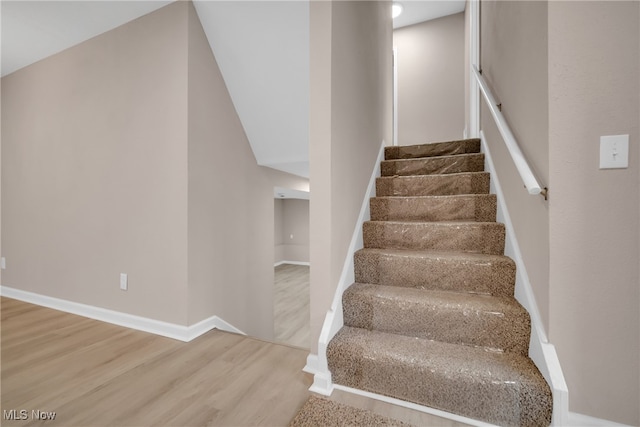 staircase featuring hardwood / wood-style flooring and lofted ceiling