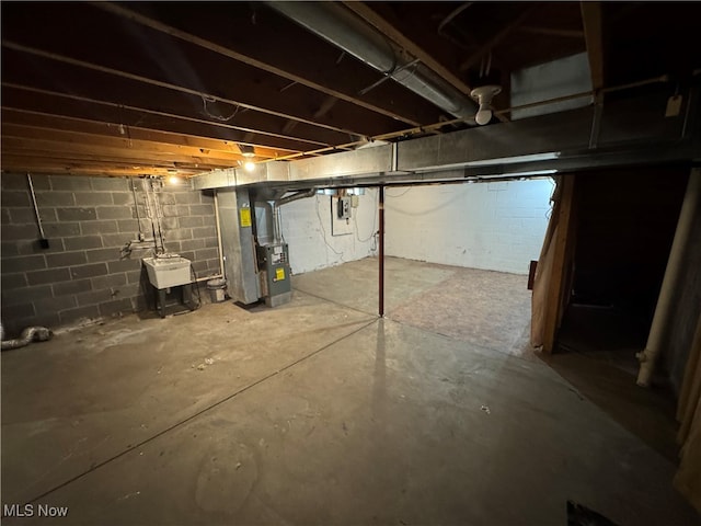 basement featuring sink, electric panel, and heating unit