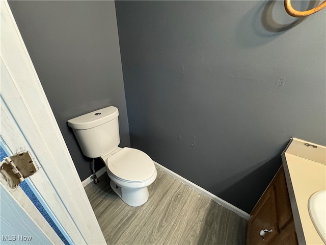 bathroom with wood-type flooring, vanity, and toilet