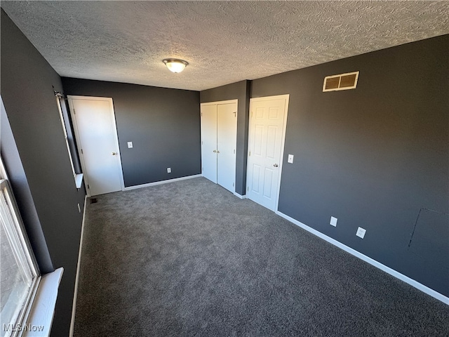 unfurnished bedroom with dark carpet and a textured ceiling