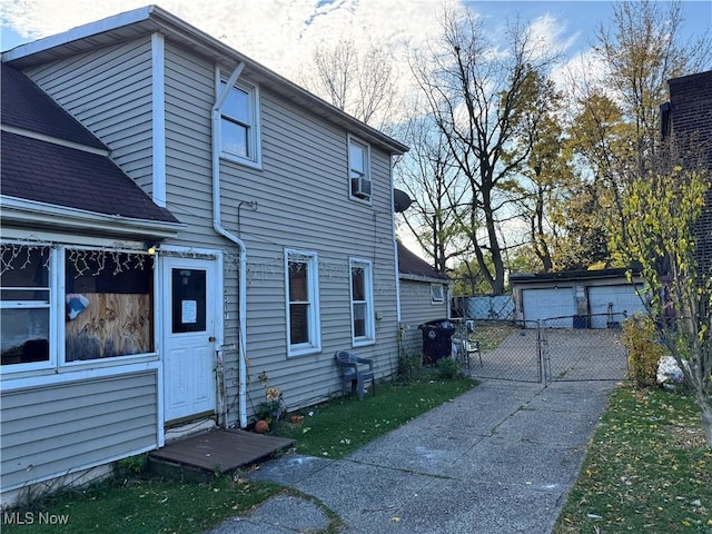 view of side of property featuring an outbuilding, fence, a detached garage, and a gate