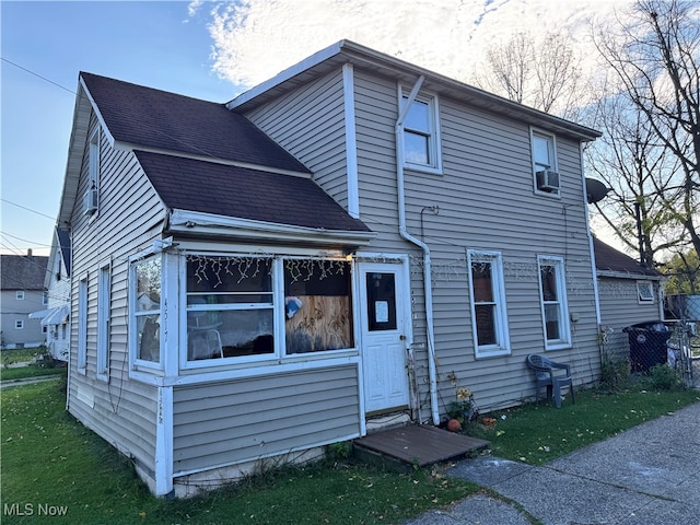 rear view of property featuring cooling unit and a shingled roof