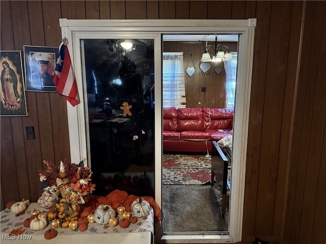 doorway to outside with wooden walls and a chandelier