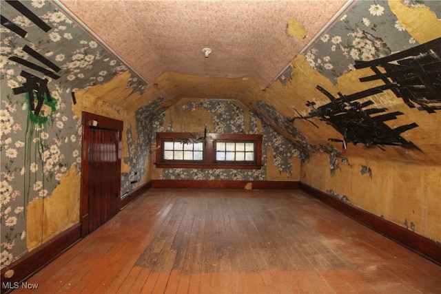 additional living space with wood-type flooring and vaulted ceiling