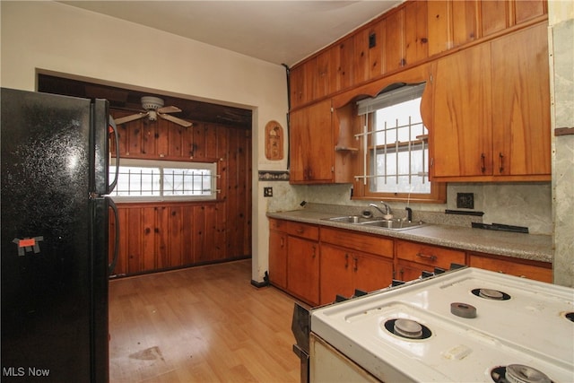 kitchen with tasteful backsplash, black fridge, white range with electric stovetop, sink, and light hardwood / wood-style flooring