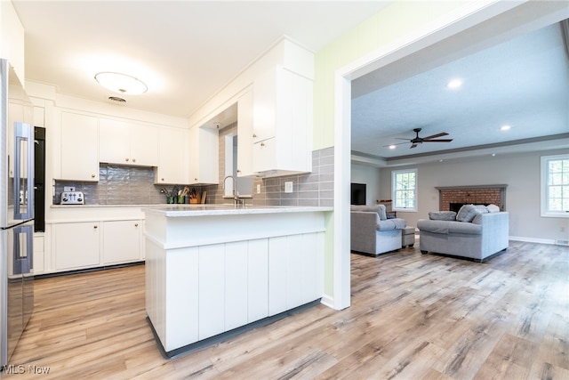 kitchen featuring white cabinets, a healthy amount of sunlight, kitchen peninsula, and light hardwood / wood-style floors