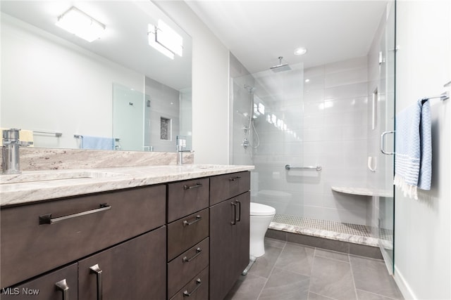 bathroom featuring tile patterned floors, vanity, a shower with shower door, and toilet