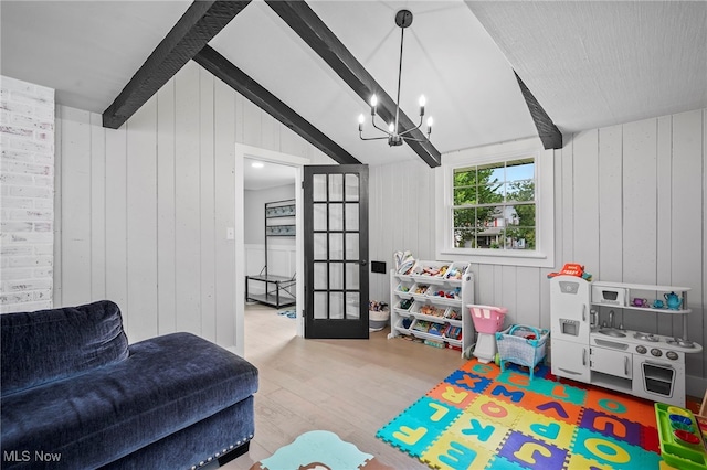 game room featuring light wood-type flooring, lofted ceiling with beams, an inviting chandelier, and wood walls