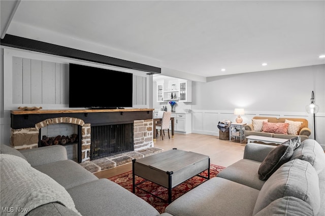 living room with a stone fireplace and light hardwood / wood-style flooring