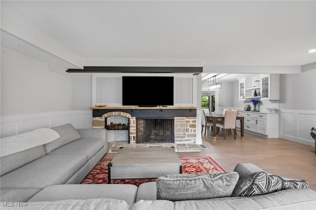 living room with a brick fireplace and light wood-type flooring