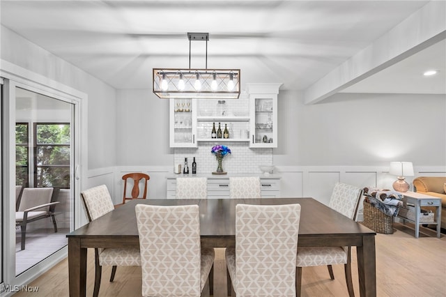 dining space featuring beamed ceiling and light wood-type flooring