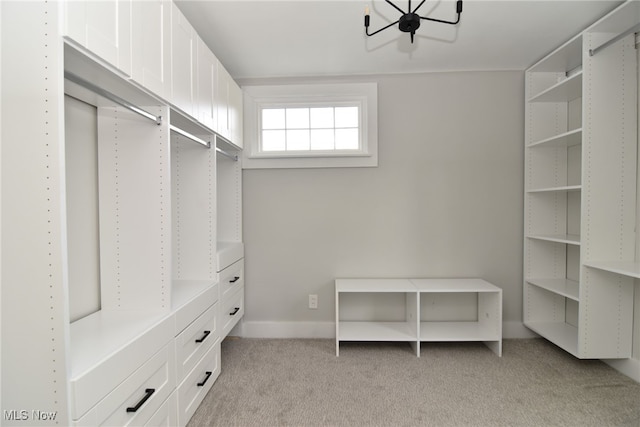 walk in closet with a notable chandelier and light carpet