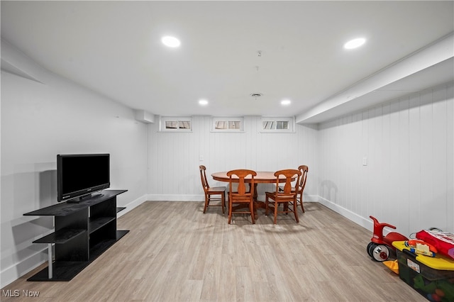 dining space featuring light wood-type flooring and wooden walls