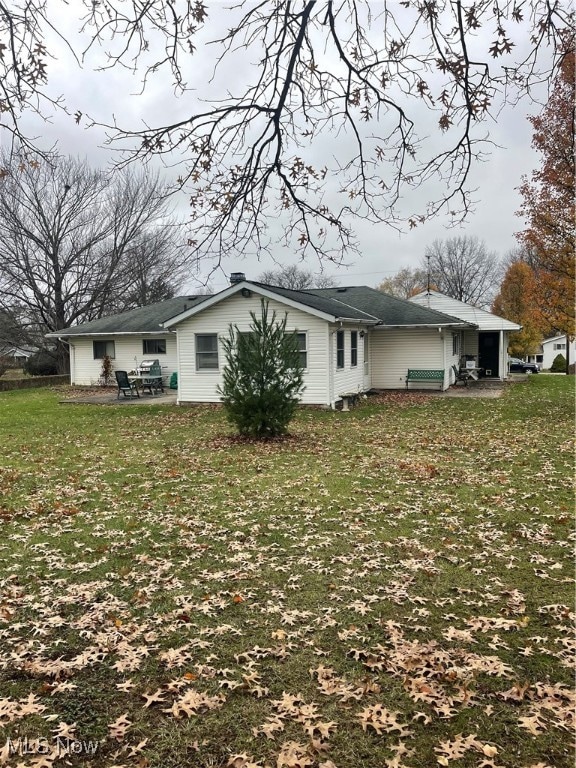 rear view of property featuring a lawn and a patio area