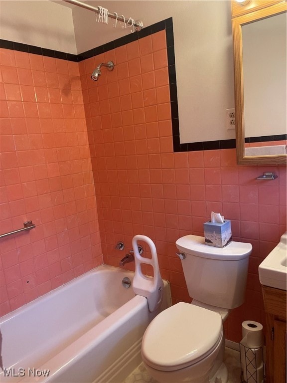 full bathroom with vanity, toilet, tile walls, and tiled shower / bath