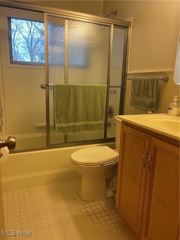 full bathroom with combined bath / shower with glass door, vanity, tile patterned flooring, and toilet