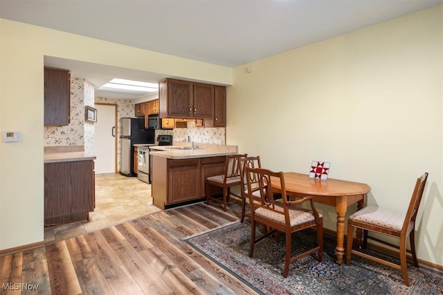 kitchen featuring kitchen peninsula, stainless steel appliances, light hardwood / wood-style flooring, and sink