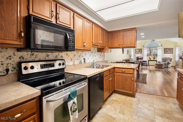 kitchen with black appliances, sink, light hardwood / wood-style flooring, ceiling fan, and kitchen peninsula